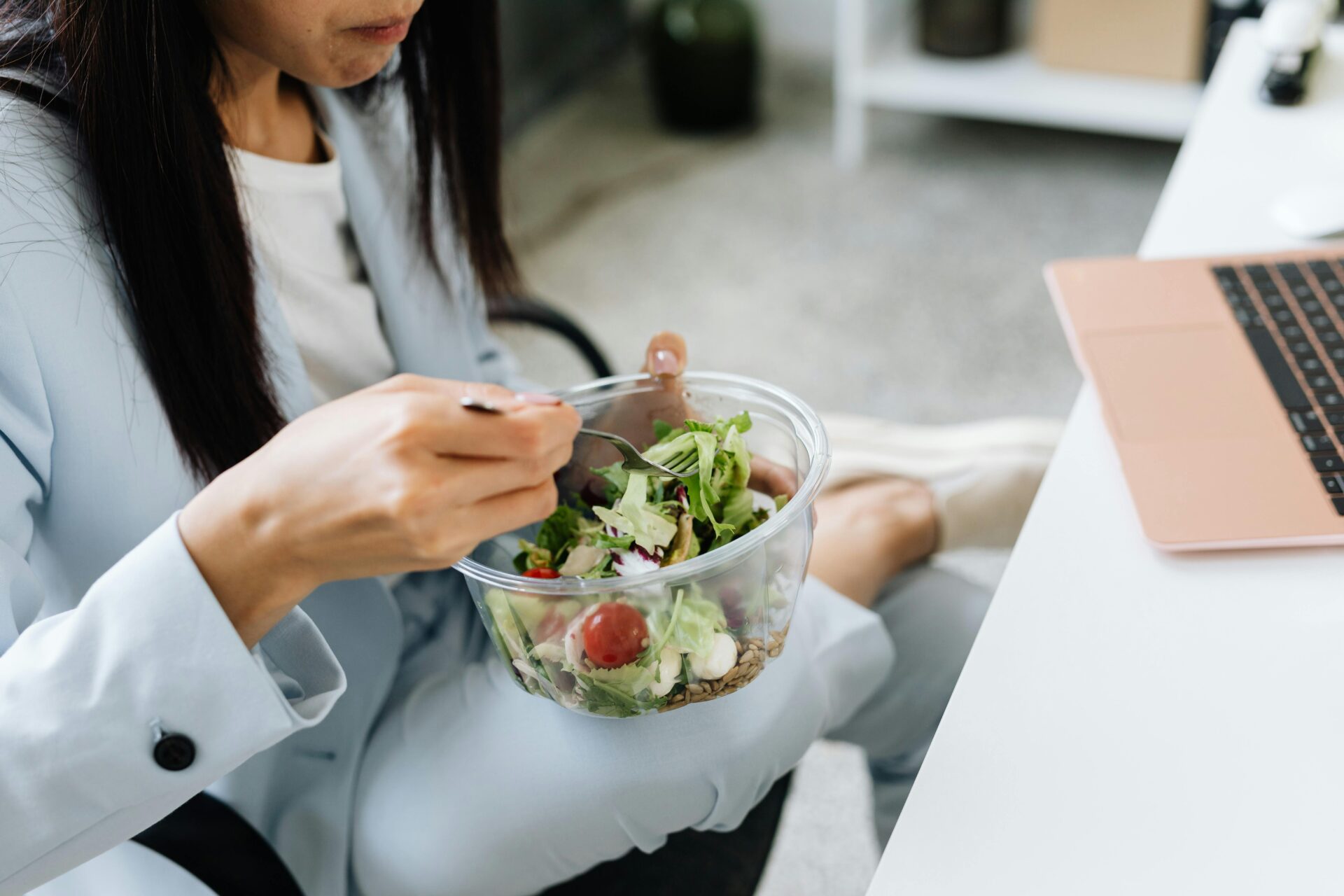 Image of woman eating salad at her desk.